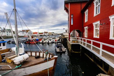 Norveç, Lofoten Adaları 'ndaki Henningsvaer manzarası liman boyunca uzanan ve arka planda dağlar bulunan geleneksel binaları gösteriyor..