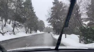 İspanya, La Molina 'da karlı bir yolda giden bir arabanın ön camına kar yağıyor.