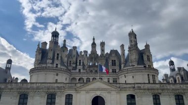 Fransız bayrağı bulutlu gökyüzünün altında Chambord kalesinde dalgalanıyor