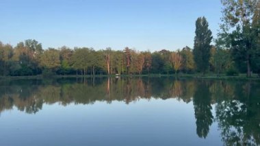Fransa, Guesnes Gölü 'ndeki sakin su ağaçları ve gökyüzünü yansıtıyor.