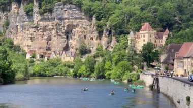 Kayakçılar, La Roque Gageac köyünün yakınlarındaki Dordogne nehrinde kürek çekiyorlar.