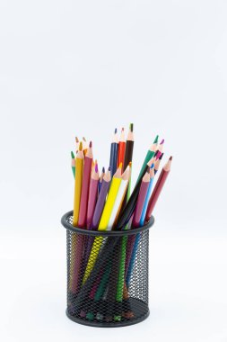 Beyaz arka planda siyah metal bir kalem tutacağının içinde duran renkli kalemler grubu, çizim ve çizim için hazır.