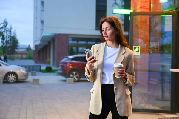 Günlük kıyafetler giymiş güzel bir kadın şehir ortamında bir fincan kahvenin tadını çıkarıyor. Telefonuyla konuşurken derin bir sohbete dalmış gibi görünüyor. Hem odaklanmış hem de memnun olduğunu gösteren bir ifadeyle..