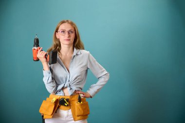 Koruyucu kasklı genç bir kadın işçi arka planda izole edilmiş bir ev planı tutuyor. Güzel gülümseyen beyaz kadın mimar yeni bir proje planlıyor. İnsanlar mimarlık projesinde çalışıyor