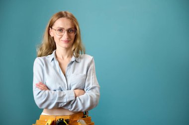 Arka planda çapraz elleri olan genç kadın işçinin portresi. Yeni bir proje planlayan beyaz bir kadın. Stüdyoda portre. Boşluğu kopyala.