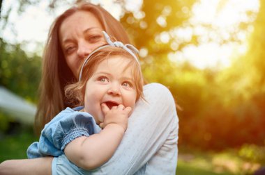Anne ve kızı bahçede oynuyorlardı. Güzel bir aile dışarıda poz veriyor. Yaz manzarasında küçük mutlu bir kız. Tatlı küçük çocuk dışarıda.