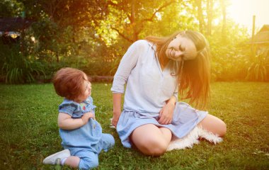 Anne ve kızı bahçede oynuyorlardı. Güzel bir aile dışarıda poz veriyor. Yaz manzarasında küçük mutlu bir kız. Tatlı küçük çocuk dışarıda.