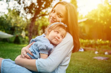 Anne ve kızı bahçede oynuyorlardı. Güzel bir aile dışarıda poz veriyor. Yaz manzarasında küçük mutlu bir kız. Tatlı küçük çocuk dışarıda.