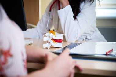 Hasta ve öğrencilere omurga anatomisini gösteren genç kadın nörolog ya da profesörün portresi. Bir hastaya omurga ameliyatını açıklayan güzel kadın cerrahın ya da nörologun portresi. Kapat.