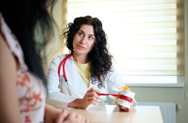 Hasta ve öğrencilere omurga anatomisini gösteren genç kadın nörolog ya da profesörün portresi. Bir hastaya omurga ameliyatını açıklayan güzel kadın cerrahın ya da nörologun portresi. Kapat.