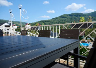 Geniş açı, teras manzarası, bir masa ve güneşten bir şemsiye. Dağlarda dinlenmek için bir daire. Karpatya dağlarında tatil yeri.