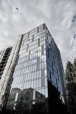 Yeni iş bölgesinde mavi gökyüzüne karşı modern binanın alt manzarası. Modern bir apartmanın ön cephesi. Kentsel bina tasarımı konsepti. Ivano-Frankivsk, Ukrayna - 09.26.2023