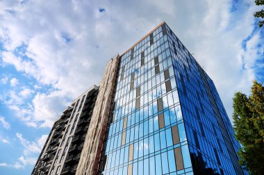 Yeni iş bölgesinde mavi gökyüzüne karşı modern binanın alt manzarası. Modern bir apartmanın ön cephesi. Kentsel bina tasarımı konsepti. Ivano-Frankivsk, Ukrayna - 09.26.2023