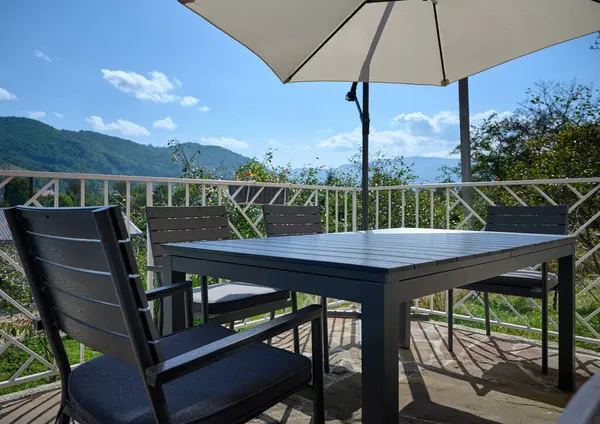 Wide angle, view of the terrace with a table and an umbrella from the sun. Apartment for rest in the mountains. Resort in Carpathian mountains.
