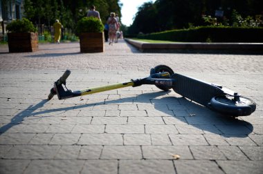 Kırık elektrikli scooter yolda yatıyor. Bir scooter kirala. Şehir ulaşımı.