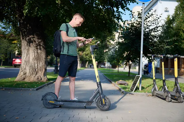 Genç bir turist elektroşok cihazı alıyor. Akıllı telefonunu scooter 'a bağlamaya çalışan odaklanmış bir adam. Genç erkek elektrikli aracın nasıl kullanıldığını anlayamaz..