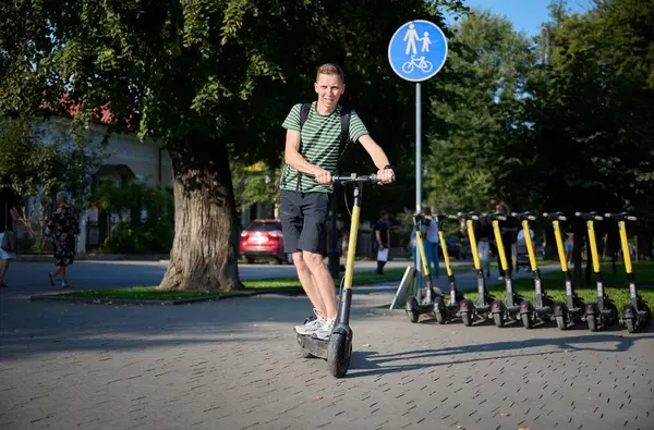 Parkta elektrikli scooter kullanan genç bir adam..