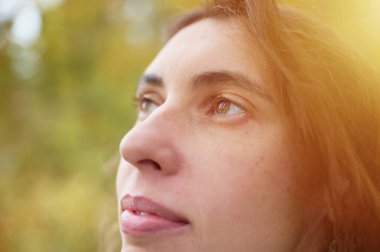 Modern giysiler içinde gülen güzel bir kadının sonbahar ormanında yürüyen portresi. Sonbahar ormanında gülümseyen çekici bir kadın. Güzel bayan beyaz kazak ve göz kamaştırıcı bir bilezik giyiyor..