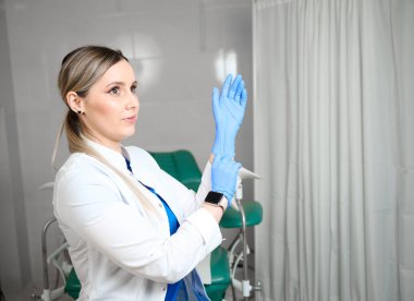 Pretty female doctor gynecologist in blue medical sterile gloves preparing for vaginal examination. Women's health. Prevention illness. Early detection of cancer. Check up clipart