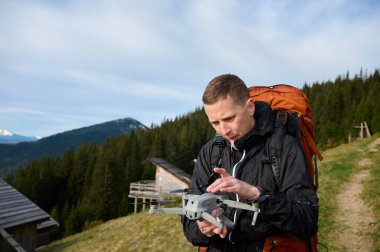 Tam donanımlı gezgin elinde uzaktan kumanda ve insansız hava aracı tutuyor. Elden uçmaya başla. Drone Pilot, Drone kamerasını elinden bırakıyor. Hava doğa fotoğrafçılığı ve videografi.