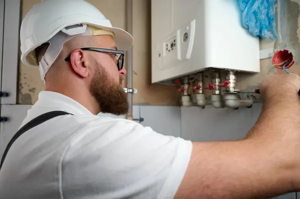 Tesisatçı bir kazan kurdu. Profesyonel mühendis eve gaz kazanı kuruyor ve iç ısıtma sisteminin bağlantılarını ve borularını kontrol ediyor. Isıtma sistemini ayarlayan Kazan Kurma Servisi.