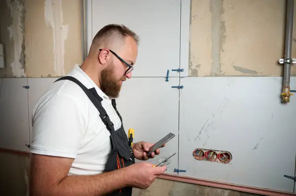 stock image Professional electrician installing electric socket into the wall using screwdriver in a new house. Electrical repairs at home. Electrician mounting wiring triple socket with an electrical screwdriver