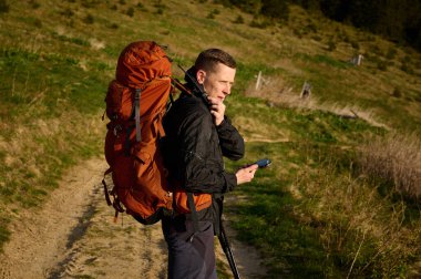 Tam teçhizatlı bir yürüyüşçü dağın zirvesinde telsizle konuşuyor. Radyoda konuşan bir turist. Kaşif, dağlarda seyahat ederken radyo istasyonuyla konuşuyor..