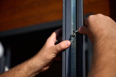 Yeni bir inşaat sahasına kapı ve pencere döşeyen işçilerin yakın görüntüsü. Büyülü anahtarı olan üniformalı bir adam yeni güzel evin ön cam kapısını ve pencerelerini ayarlıyor. Ekin görünümü.