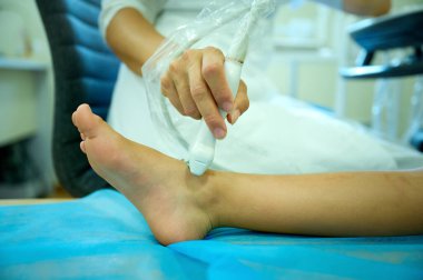 Pediatrik ultrason taraması. Çocuk ultrasonu. Ayak taraması yapan çocuk doktoru. Doktorun çocuk için ayak sonogramı yapmasına yakın çekim. İskelet sisteminin ultrason incelemesi. Eklem hastalıkları konsepti