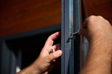 Yeni bir inşaat sahasına kapı ve pencere döşeyen işçilerin yakın görüntüsü. Büyülü anahtarı olan üniformalı bir adam yeni güzel evin ön cam kapısını ve pencerelerini ayarlıyor. Ekin görünümü.