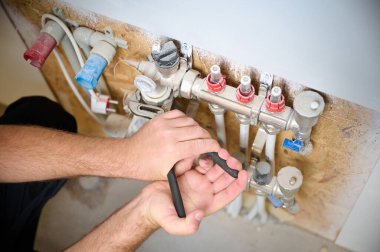 Adam yeni bir dairede ısıtma sistemini ayarlıyor. Tesisatçı merkezi sistem vanalarındaki ısıyı ayarlıyor. Servis elemanı ısıtma sistemini ayarlıyor. Yeraltı ısıtma sistemi. Ekin görünümü