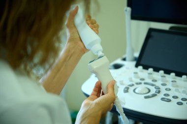 Doktor elinde ultrason sondası ile klinikte taramaya hazırlanıyor. Doktor ultrason tarayıcısını ultrason işlemi için hazırlıyor. Tıp bürosu. Ultrason makinesiyle taramaya hazır.