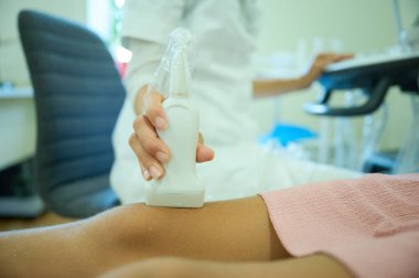 Pediatrik ultrason taraması. Çocuk ultrasonu. Çocuk doktoru bacağını tarıyor. Doktorun çocuk için bacak sonogramı yapmasına yakın çekim. İskelet sisteminin ultrason incelemesi. Eklem hastalıkları konsepti