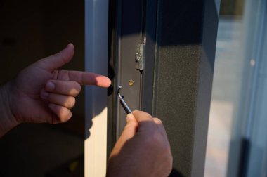 Yeni bir inşaat sahasına kapı ve pencere döşeyen işçilerin yakın görüntüsü. Büyülü anahtarı olan üniformalı bir adam yeni güzel evin ön cam kapısını ve pencerelerini ayarlıyor. Ekin görünümü.