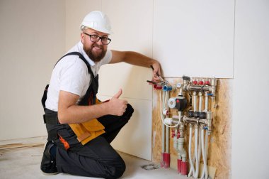 Adam yeni bir dairede ısıtma sistemini ayarlıyor. Tesisatçı merkezi sistem vanalarındaki ısıyı ayarlıyor. Servis elemanı ısıtma sistemini ayarlıyor. Yeraltı ısıtma sistemi. Adam boruyu kontrol ediyor