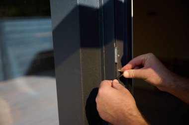 Close up view of worker installing door and window in a new house construction site. Man in uniform with hex key adjusting front glass door and windows in new beautiful house. Crop view. clipart