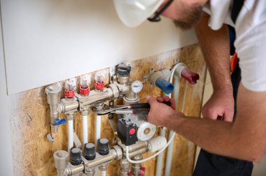 Adam yeni bir dairede ısıtma sistemini ayarlıyor. Tesisatçı merkezi sistem vanalarındaki ısıyı ayarlıyor. Servis elemanı ısıtma sistemini ayarlıyor. Yeraltı ısıtma sistemi. Ekin görünümü