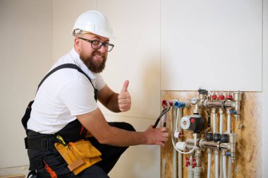 Adam yeni bir dairede ısıtma sistemini ayarlıyor. Tesisatçı merkezi sistem vanalarındaki ısıyı ayarlıyor. Servis elemanı ısıtma sistemini ayarlıyor. Yeraltı ısıtma sistemi. Adam boruyu kontrol ediyor
