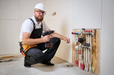 Adam yeni bir dairede ısıtma sistemini ayarlıyor. Tesisatçı merkezi sistem vanalarındaki ısıyı ayarlıyor. Servis elemanı ısıtma sistemini ayarlıyor. Yeraltı ısıtma sistemi. Adam boruyu kontrol ediyor