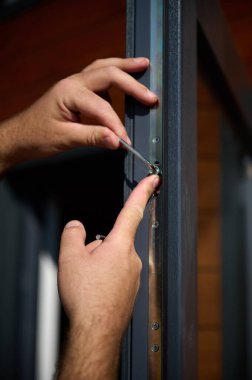 Yeni bir inşaat sahasına kapı ve pencere döşeyen işçilerin yakın görüntüsü. Büyülü anahtarı olan üniformalı bir adam yeni güzel evin ön cam kapısını ve pencerelerini ayarlıyor. Ekin görünümü.