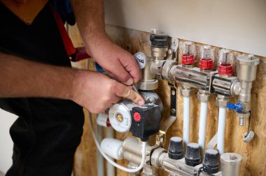 Adam yeni bir dairede ısıtma sistemini ayarlıyor. Tesisatçı merkezi sistem vanalarındaki ısıyı ayarlıyor. Servis elemanı ısıtma sistemini ayarlıyor. Yeraltı ısıtma sistemi. Ekin görünümü