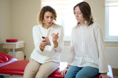 Kadın doktor, tedavi odasındaki hastaya danışmanlık yapıyor. Osteopatik tıp ve fizyoterapi konsepti. İki güzel kız arasındaki sohbet. İki kadın arasındaki iletişim