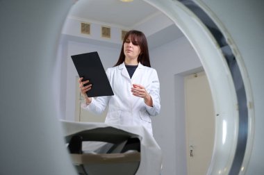 Genç bayan radyologlar tomografi odasında kalıyorlar. Klinikte çalışıyorum. Güzel doktor röntgen, röntgen, tomografi ve MRI 'ya bakıyor. Üniformalı doktor.