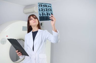 Genç bayan radyologlar tomografi odasında kalıyorlar. Klinikte çalışıyorum. Güzel doktor MRI taramasına bakıyor. Beyaz takım elbiseli bir doktor. Üniformalı Radyolog.