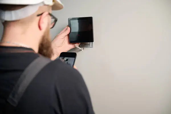 Güvenlik alarmı kurulumu. Güvenlik teknisyeni yeni ofisin duvarına güvenlik monitörü yerleştiriyor. Güvenlik sistemi kuruluyor. Adam işçi eve alarm teknolojisi sigortası kuruyor