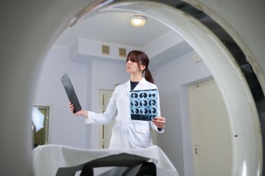 Genç bayan radyologlar tomografi odasında kalıyorlar. Klinikte çalışıyorum. Güzel doktor röntgen, röntgen, tomografi ve MRI 'ya bakıyor. Üniformalı doktor.