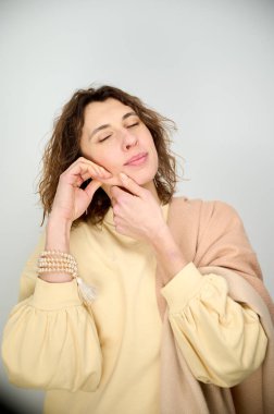 Yüz hatlarını güçlendirmek için yüz egzersizleri yapan beyaz bir kadının portresi. Yüz derisinin tazelenmesi kavramı. Cerrahi olmayan yüz kaldırma. Yüz geliştirme.