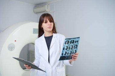 Genç bayan radyologlar tomografi odasında kalıyorlar. Klinikte çalışıyorum. Güzel doktor MRI taramasına bakıyor. Beyaz takım elbiseli bir doktor. Üniformalı Radyolog.