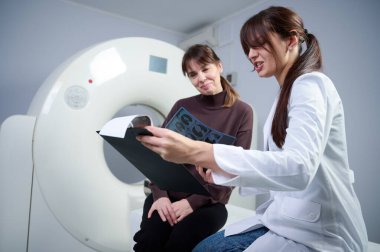 Tarama odasında hastası olan bir kadın radyolog. Tomografi odasında sevimli bir doktor. Radyolog, bilgisayarlı tomografi odasında bir kadın hasta ile birlikte. Modern klinik. Radyoloji Bölümü.