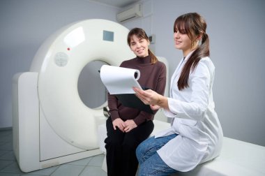 Radyolog kadın hastaya röntgen raporu gösteriyor. Tomografi odasında kendine güvenen güzel bir doktora danışmanlık yapıyor. MRI uzmanı durumu açıklıyor. Doktor ve hasta klinikte..